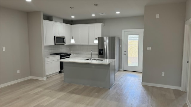 kitchen with tasteful backsplash, white cabinets, appliances with stainless steel finishes, light wood-type flooring, and a sink