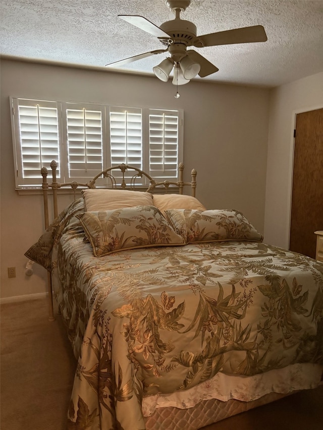 carpeted bedroom featuring baseboards, a ceiling fan, and a textured ceiling