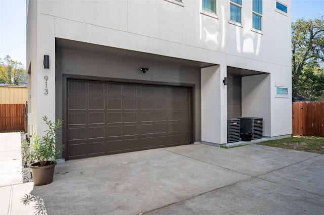 garage with central air condition unit, driveway, and fence