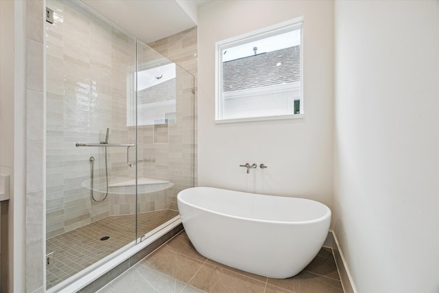 full bathroom with a stall shower, a freestanding bath, baseboards, and tile patterned floors