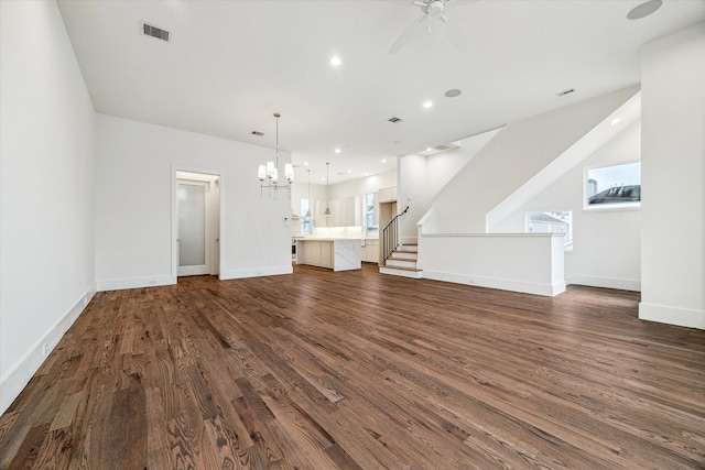 unfurnished living room with dark wood-style flooring, visible vents, baseboards, and a healthy amount of sunlight