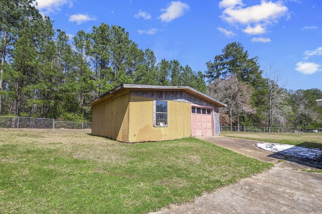 view of outbuilding with driveway, fence, and an outbuilding