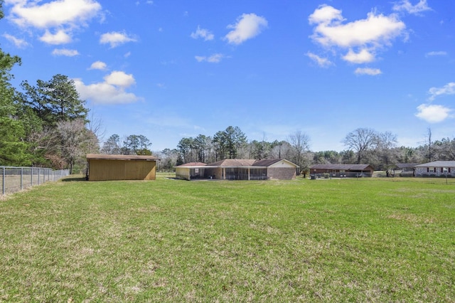 view of yard featuring a storage unit, an outdoor structure, and fence