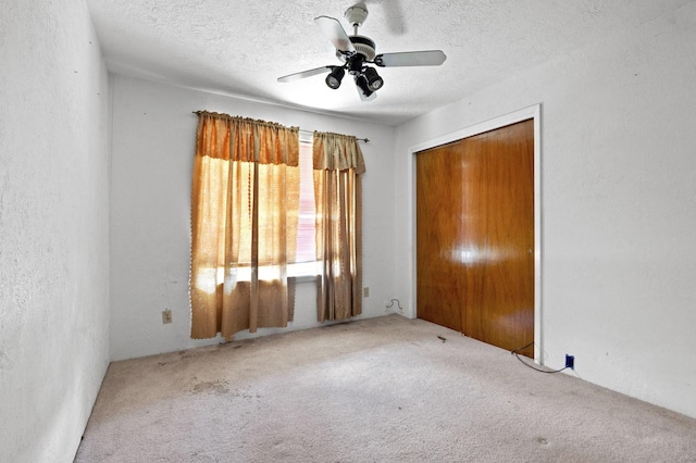 unfurnished bedroom with a textured ceiling, carpet floors, a closet, and a ceiling fan