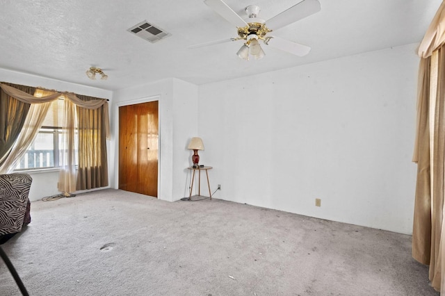 spare room featuring a ceiling fan, a textured ceiling, visible vents, and carpet flooring