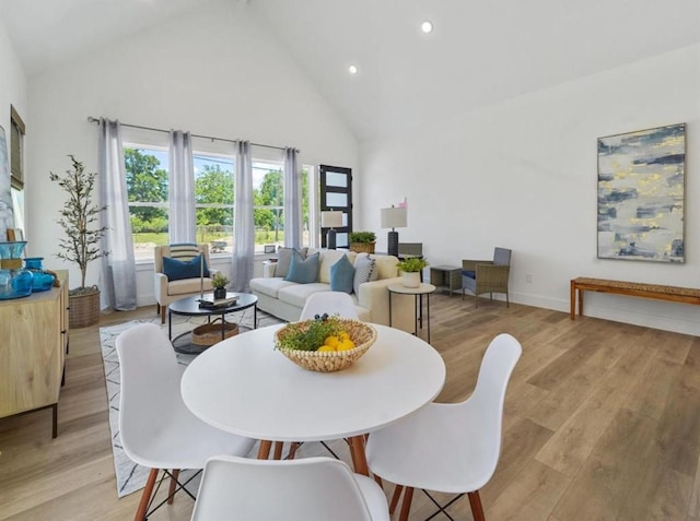 dining area featuring baseboards, high vaulted ceiling, light wood-type flooring, and recessed lighting