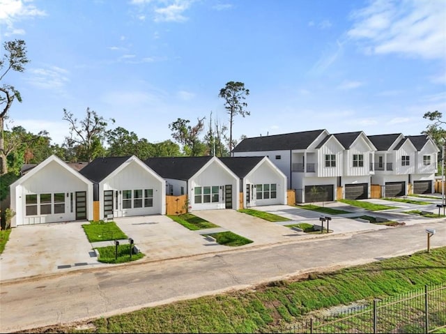 view of front facade with board and batten siding, a residential view, concrete driveway, and fence