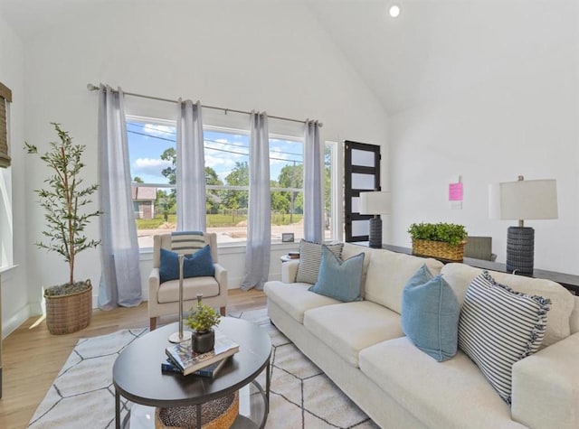 living area with light wood finished floors, baseboards, and high vaulted ceiling