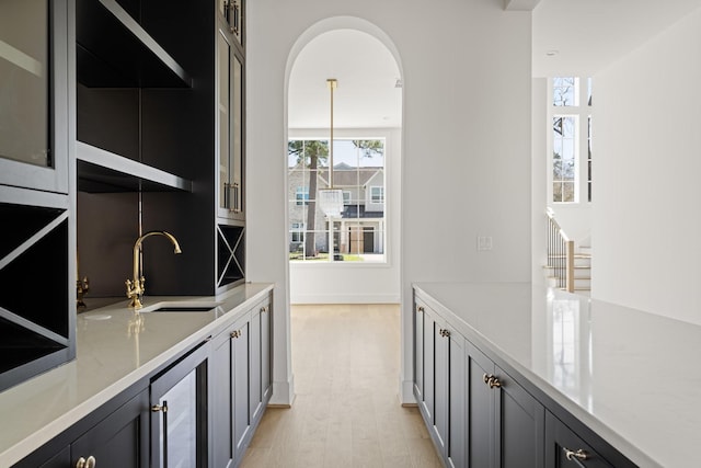 bar featuring wine cooler, decorative backsplash, light wood-style flooring, and a sink