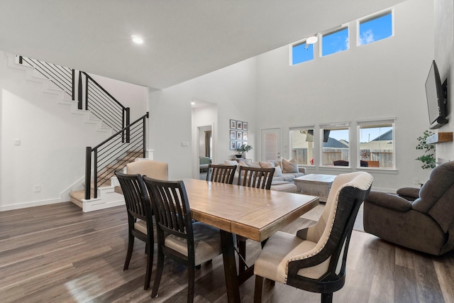 dining room with dark wood-style floors, recessed lighting, stairway, a high ceiling, and baseboards