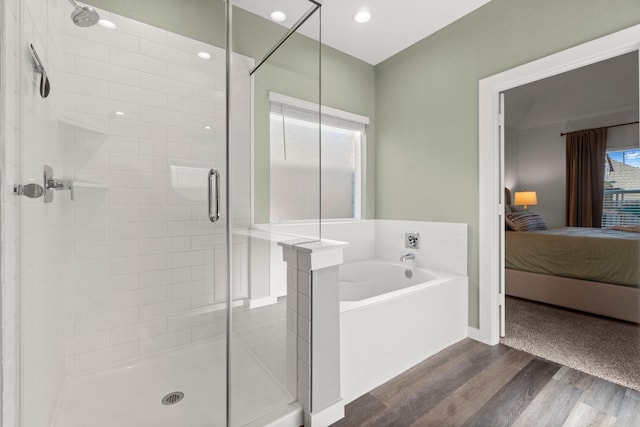 ensuite bathroom with a garden tub, connected bathroom, recessed lighting, wood finished floors, and a shower stall