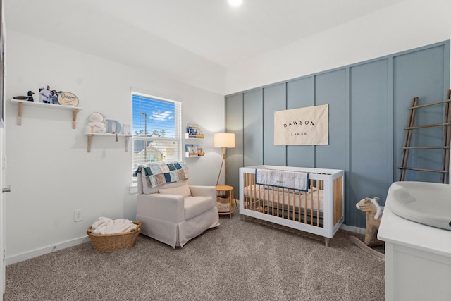 bedroom with a nursery area, baseboards, and carpet flooring