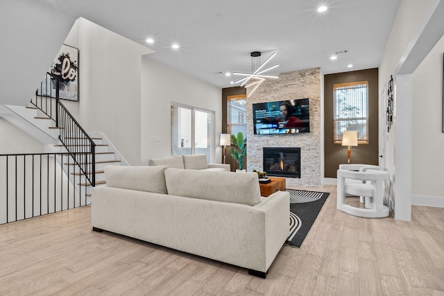 living area featuring recessed lighting, stairway, wood finished floors, and a stone fireplace