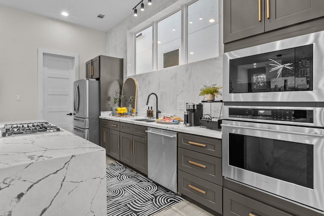 kitchen with stainless steel appliances, visible vents, glass insert cabinets, a sink, and light stone countertops