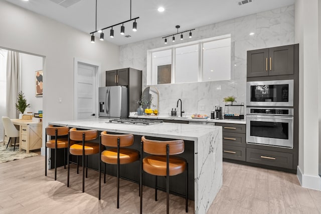 kitchen featuring light stone countertops, a kitchen bar, appliances with stainless steel finishes, and a center island