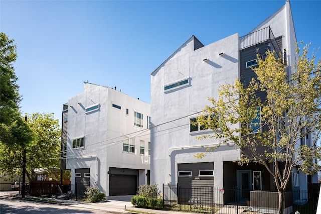 915 Thompson St, Houston, TX 77007 - view of building exterior featuring an attached garage, driveway, and fence