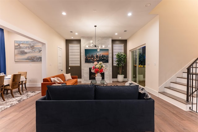 living area featuring recessed lighting, a high end fireplace, wood finished floors, baseboards, and stairs