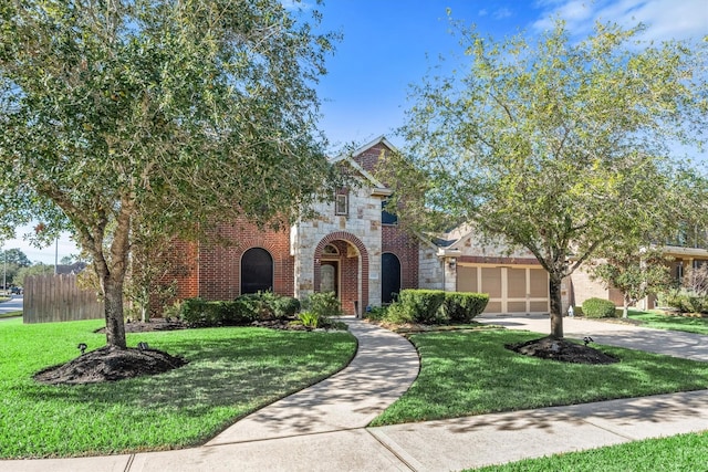 view of front facade featuring stone siding, brick siding, a front yard, and driveway