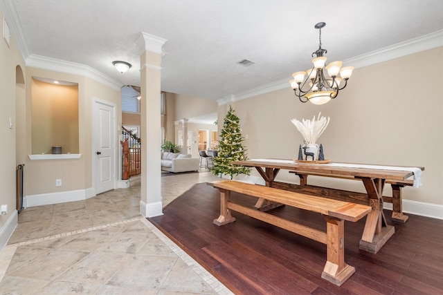 dining room featuring ornamental molding, decorative columns, light wood-style flooring, and baseboards