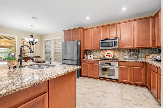 kitchen featuring appliances with stainless steel finishes, brown cabinetry, a sink, and visible vents