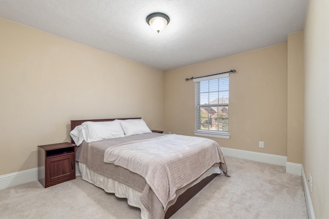 bedroom with light carpet, a textured ceiling, and baseboards