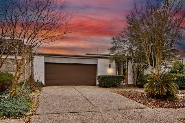 mid-century home featuring a garage, concrete driveway, and brick siding