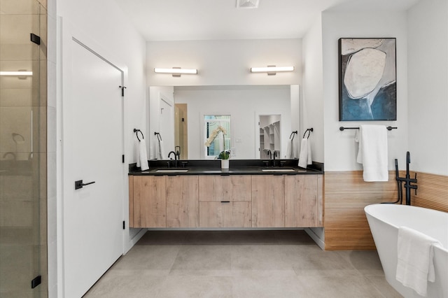 bathroom featuring a stall shower, a soaking tub, a sink, and double vanity