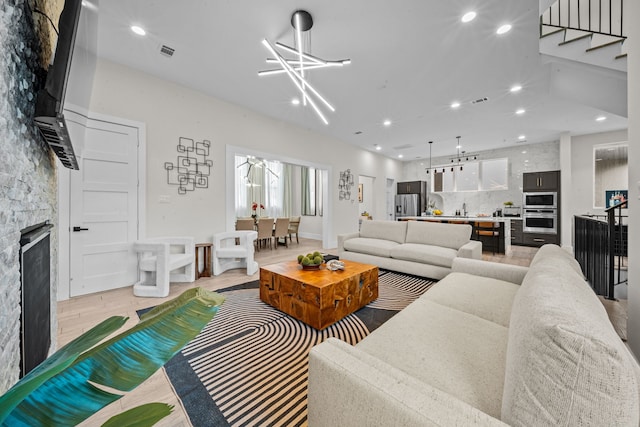 living area featuring a fireplace, recessed lighting, visible vents, light wood-style flooring, and stairs