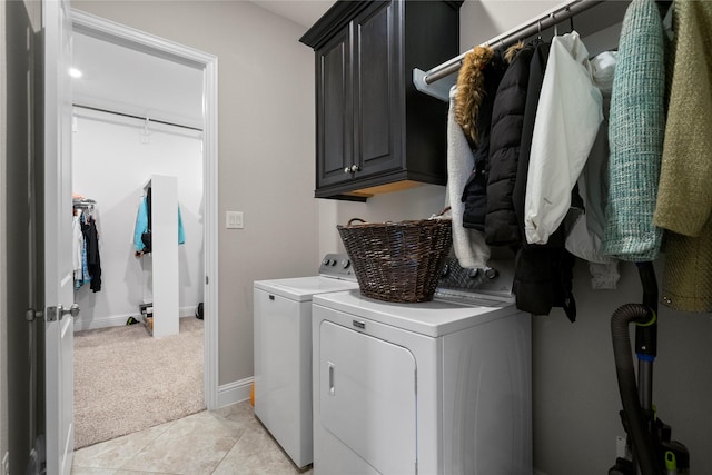 washroom featuring light tile patterned floors, light colored carpet, baseboards, cabinet space, and washer and clothes dryer