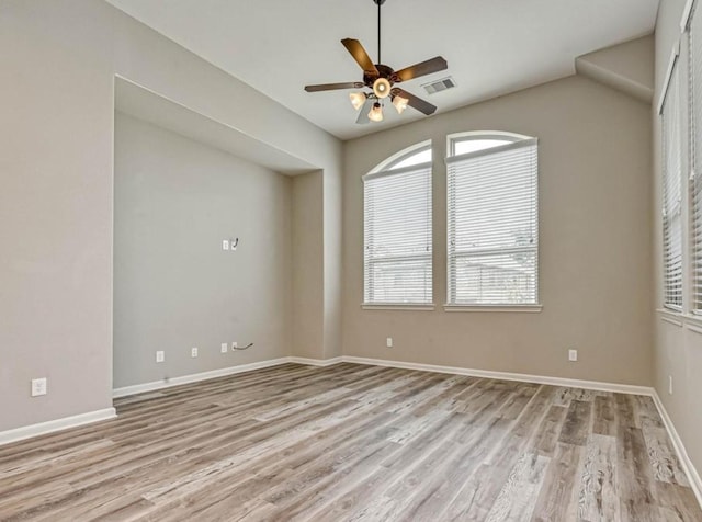 empty room featuring light wood finished floors, plenty of natural light, and visible vents