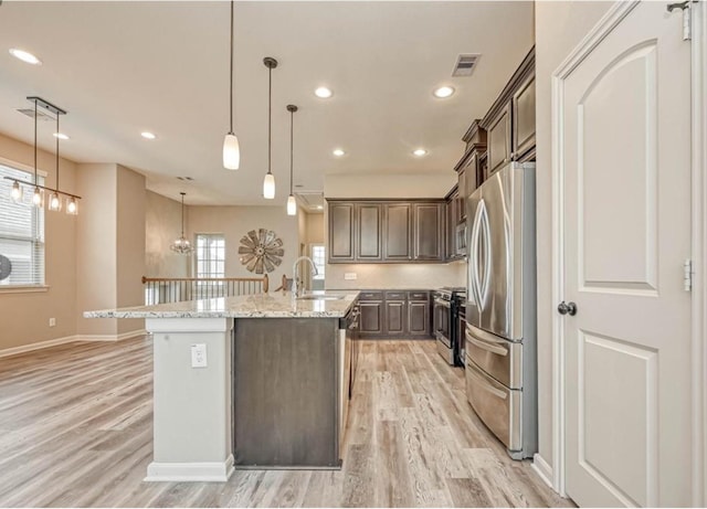 kitchen with an island with sink, dark brown cabinetry, stainless steel appliances, and a sink