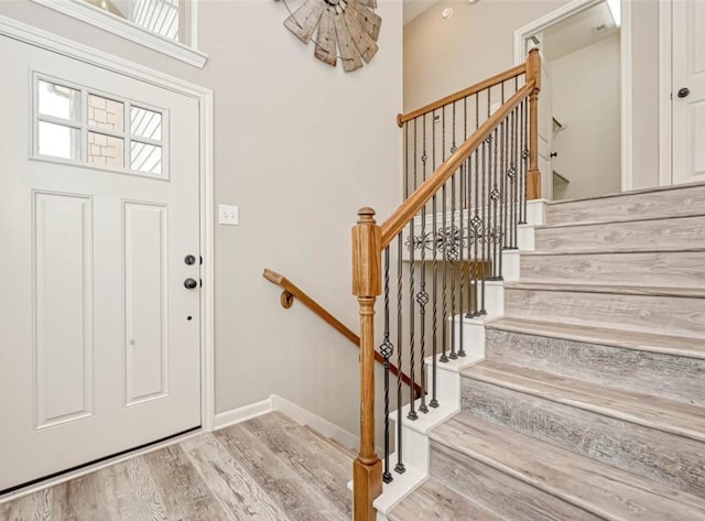 entryway with stairs, wood finished floors, and baseboards