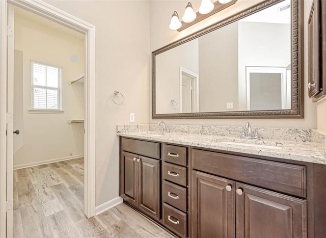 bathroom with double vanity, a sink, baseboards, and wood finished floors