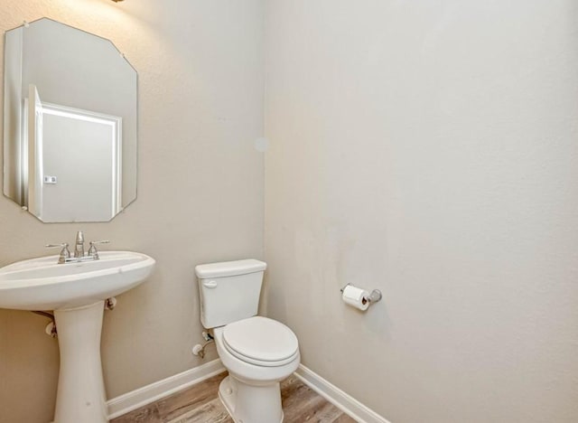 bathroom with a sink, wood finished floors, toilet, and baseboards