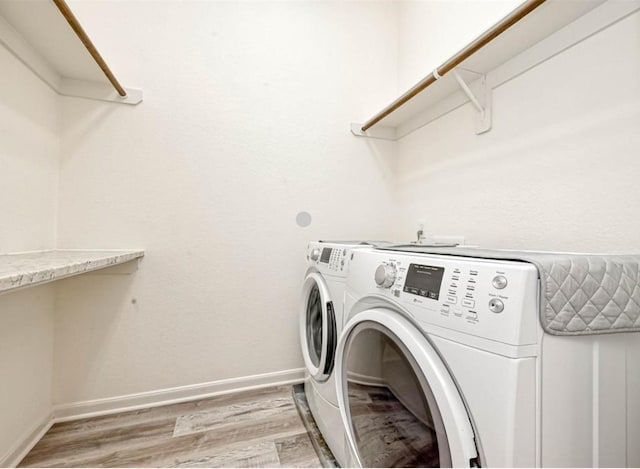 laundry room with laundry area, light wood-type flooring, washing machine and dryer, and baseboards