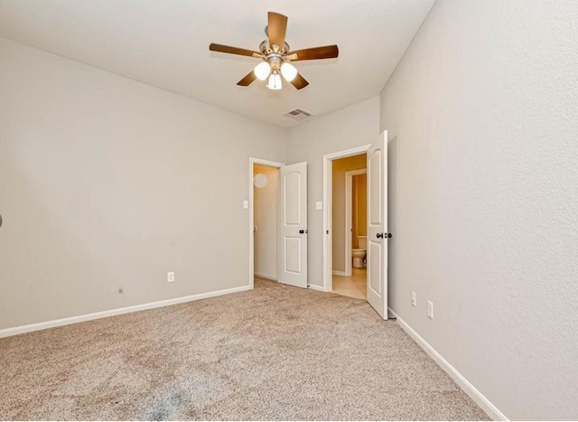 spare room with light carpet, a ceiling fan, visible vents, and baseboards