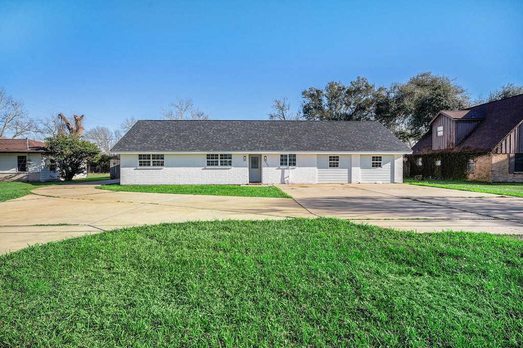 ranch-style home with concrete driveway, brick siding, and a front yard