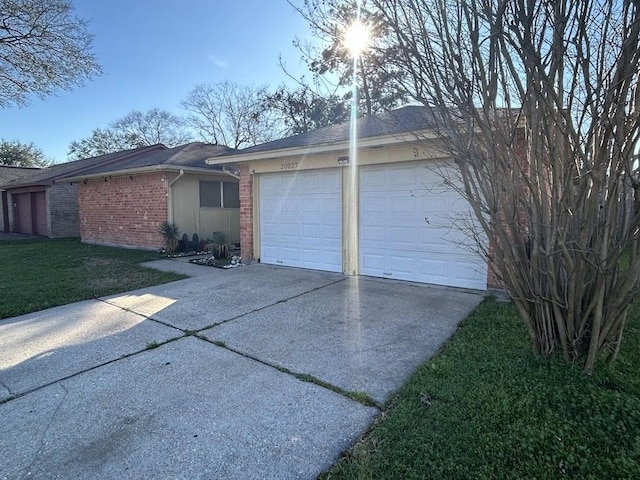 exterior space featuring brick siding, a lawn, driveway, and an attached garage