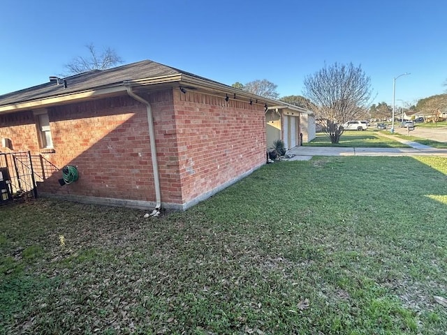 view of side of property featuring brick siding and a lawn