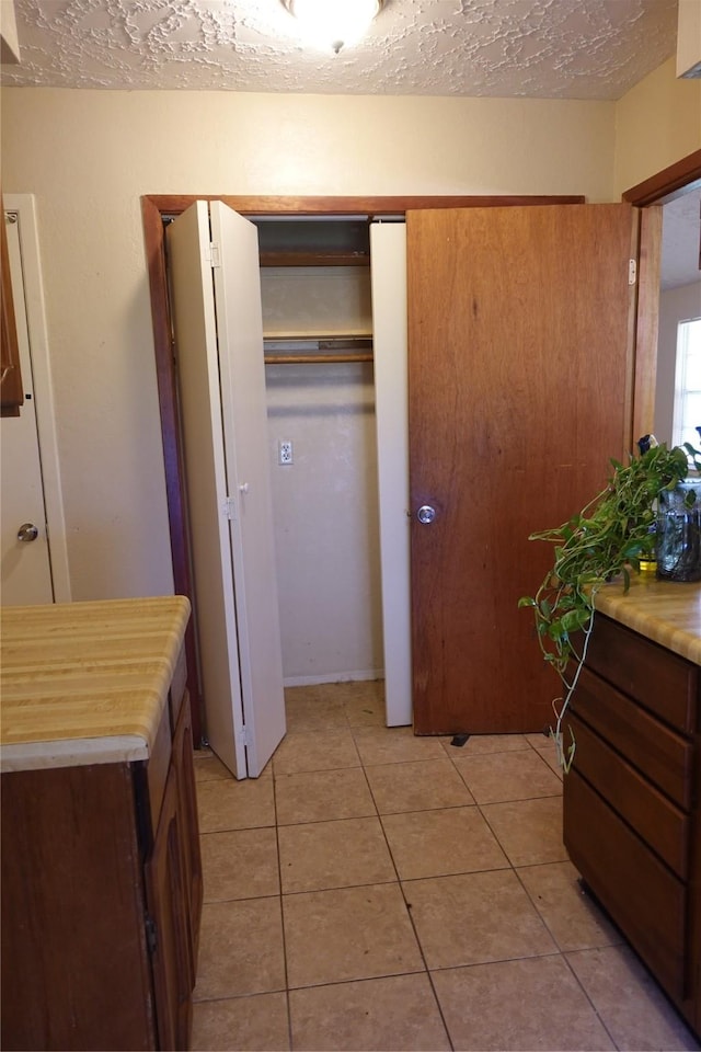 interior space featuring light tile patterned floors, a textured ceiling, and a closet