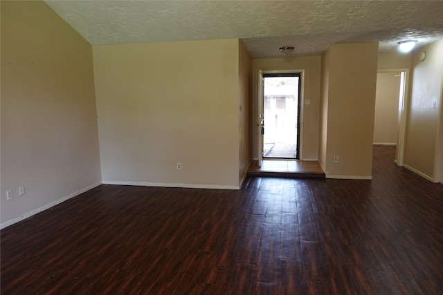 spare room featuring baseboards, a textured ceiling, and dark wood finished floors