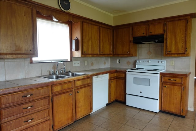 kitchen with tasteful backsplash, under cabinet range hood, brown cabinetry, white appliances, and a sink