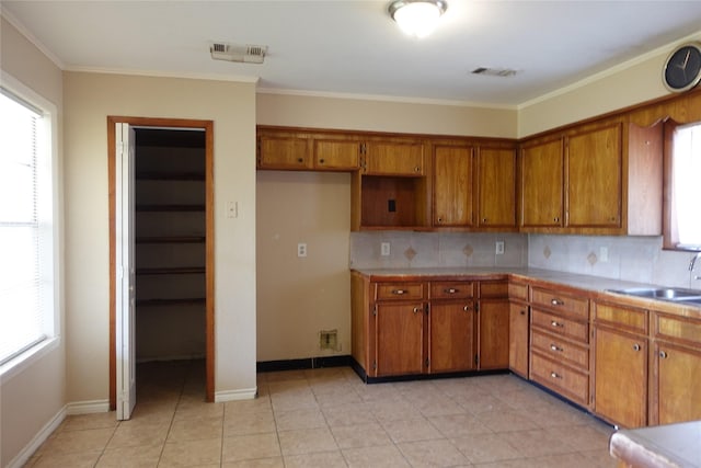 kitchen with tasteful backsplash, visible vents, brown cabinets, plenty of natural light, and a sink