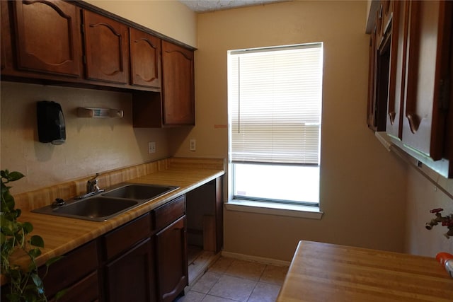kitchen with light countertops, baseboards, light tile patterned floors, and a sink