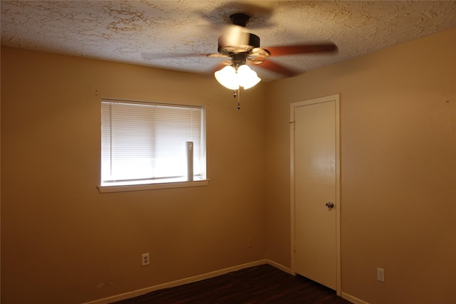 empty room with ceiling fan, baseboards, a textured ceiling, and dark wood-style floors