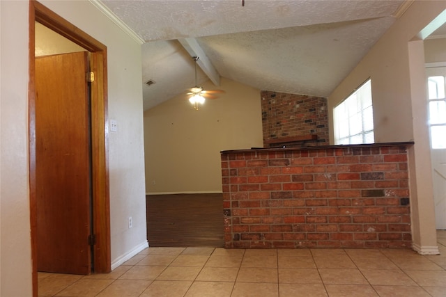 interior space with lofted ceiling with beams, a textured ceiling, light tile patterned floors, baseboards, and ceiling fan