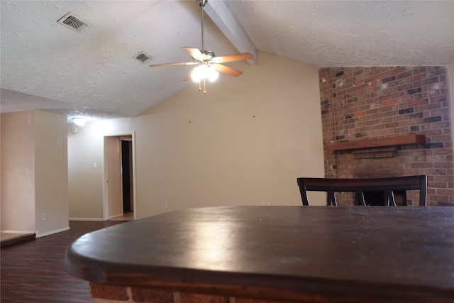 unfurnished dining area with visible vents, vaulted ceiling with beams, a fireplace, wood finished floors, and a textured ceiling