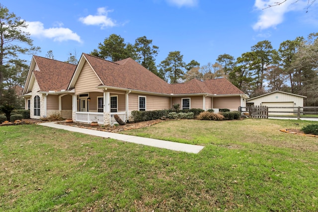 view of front facade with a shingled roof, a detached garage, fence, a front yard, and covered porch