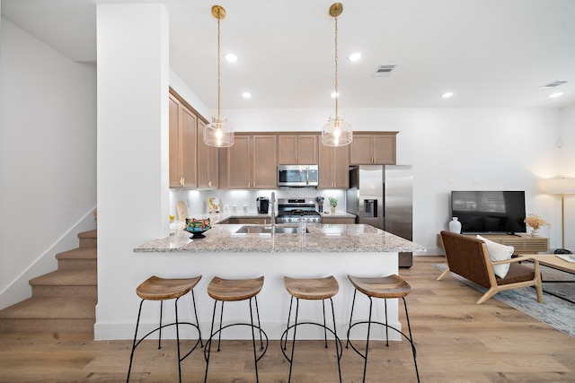 kitchen with decorative backsplash, a peninsula, stainless steel appliances, and light wood-style floors