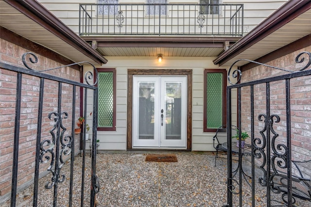 entrance to property featuring a balcony, french doors, a patio, and fence